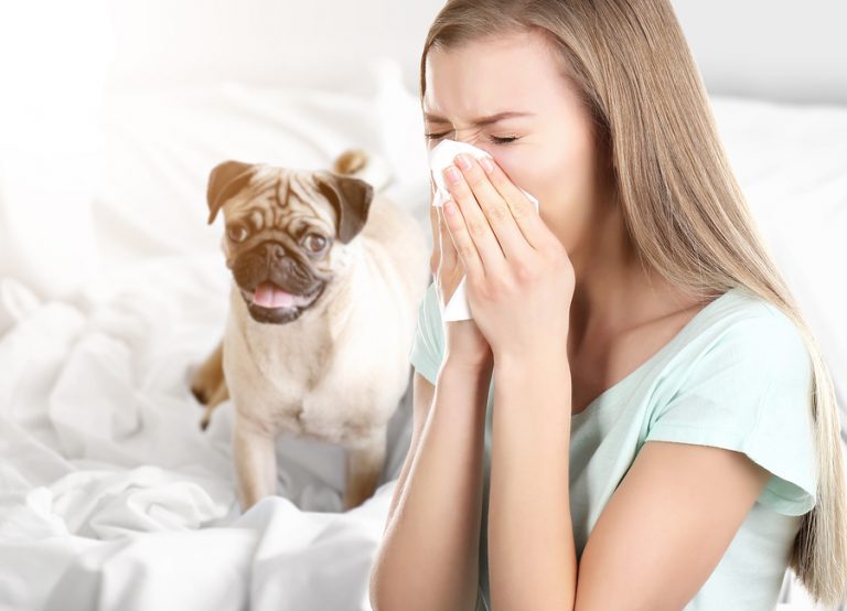 Woman sneezing with dog in background